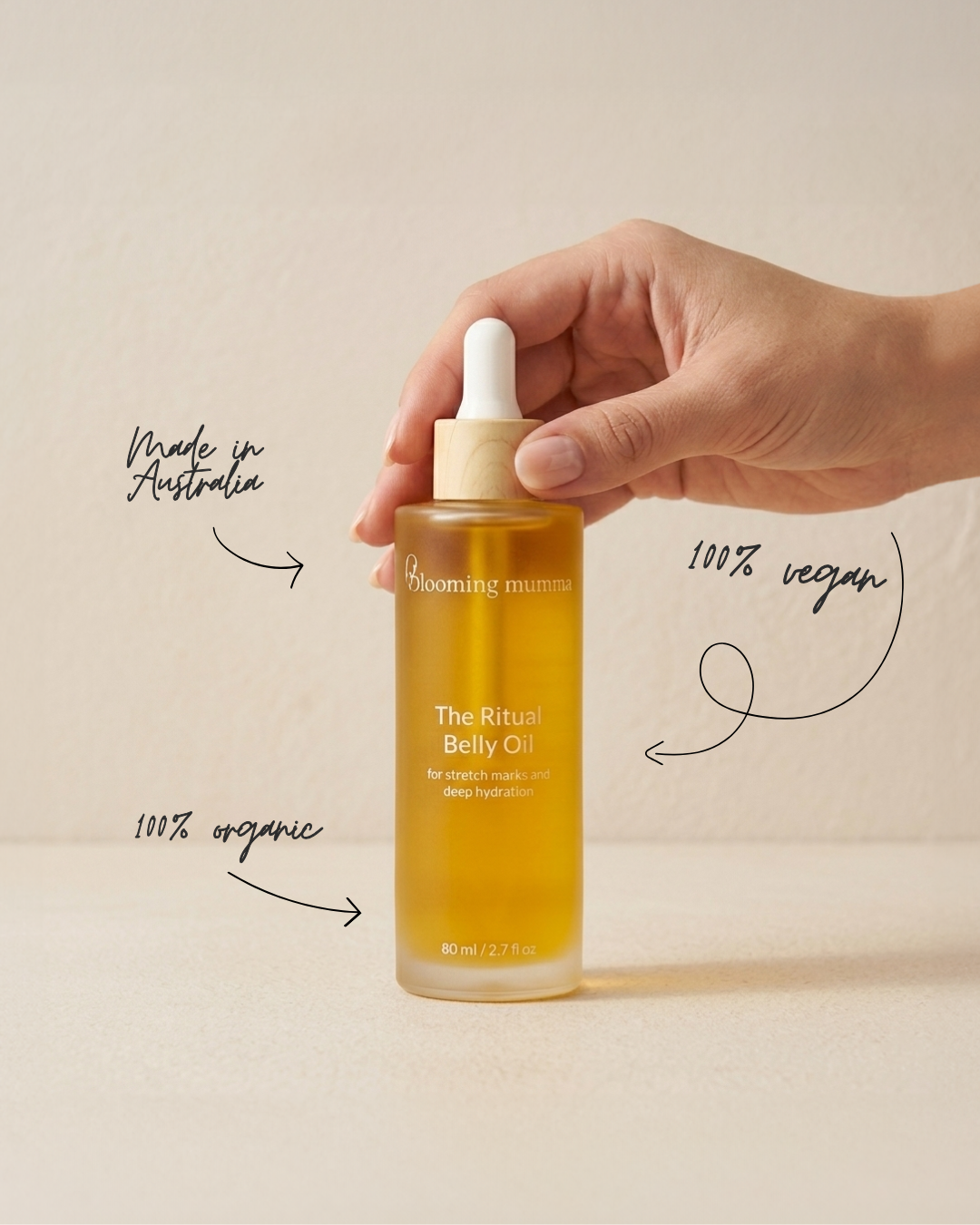 The Ritual Belly Oil bottle with a hand holding the dropper cap.
